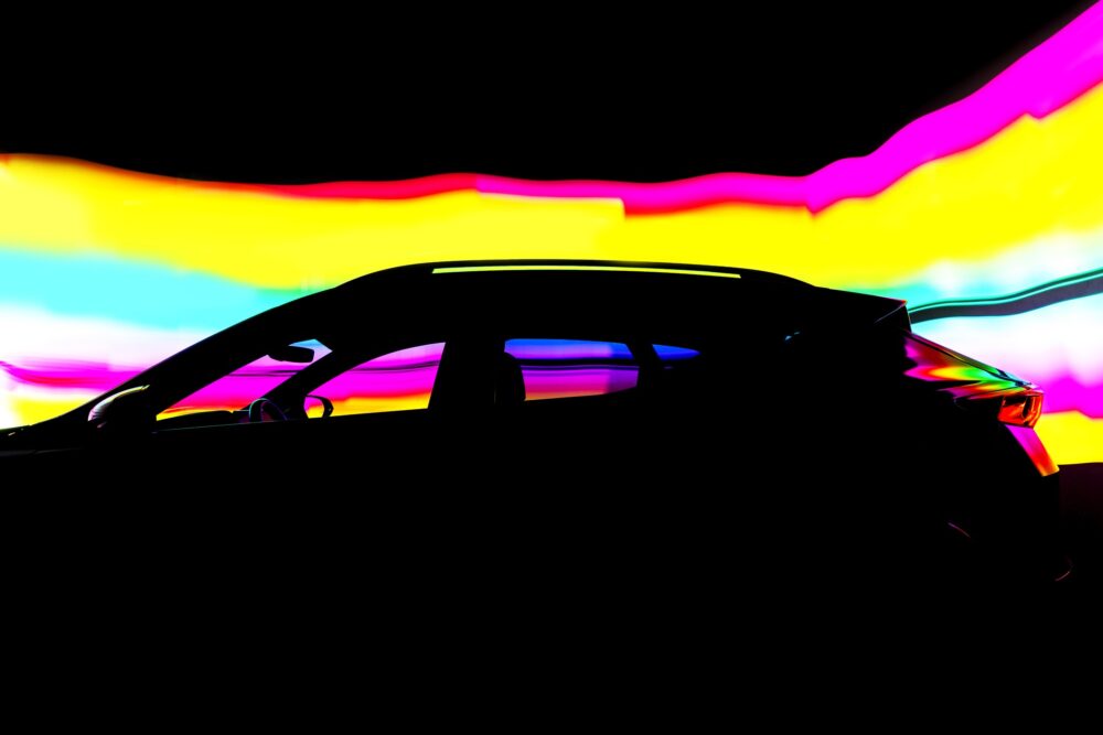 A dramatic side-profile silhouette of a modern vehicle set against vibrant colourful light trails in motion.