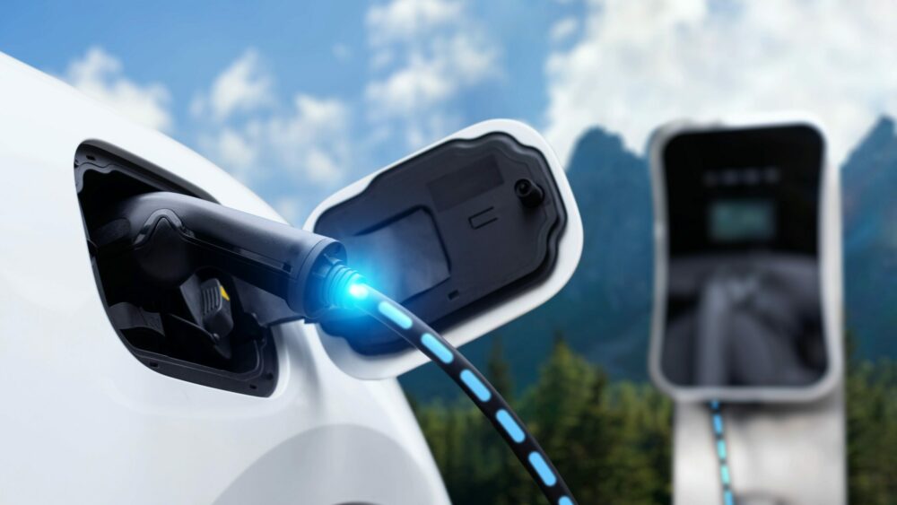 Electric car plugged in with charging station with nature background|
