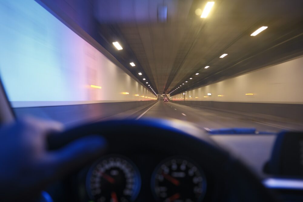 Blurred view from inside a moving car driving through a brightly lit tunnel