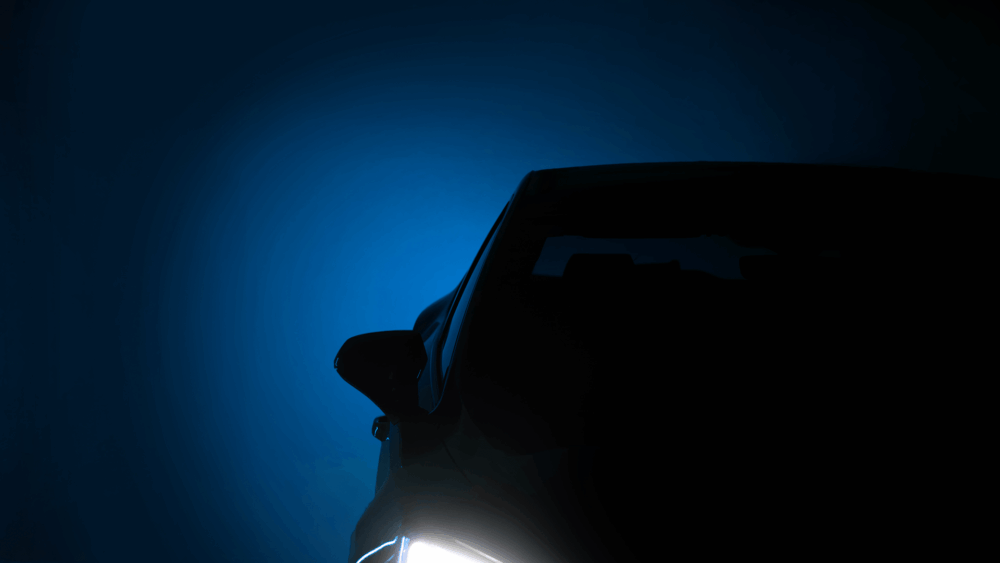 Dark graphic of a silhouette car and headlights